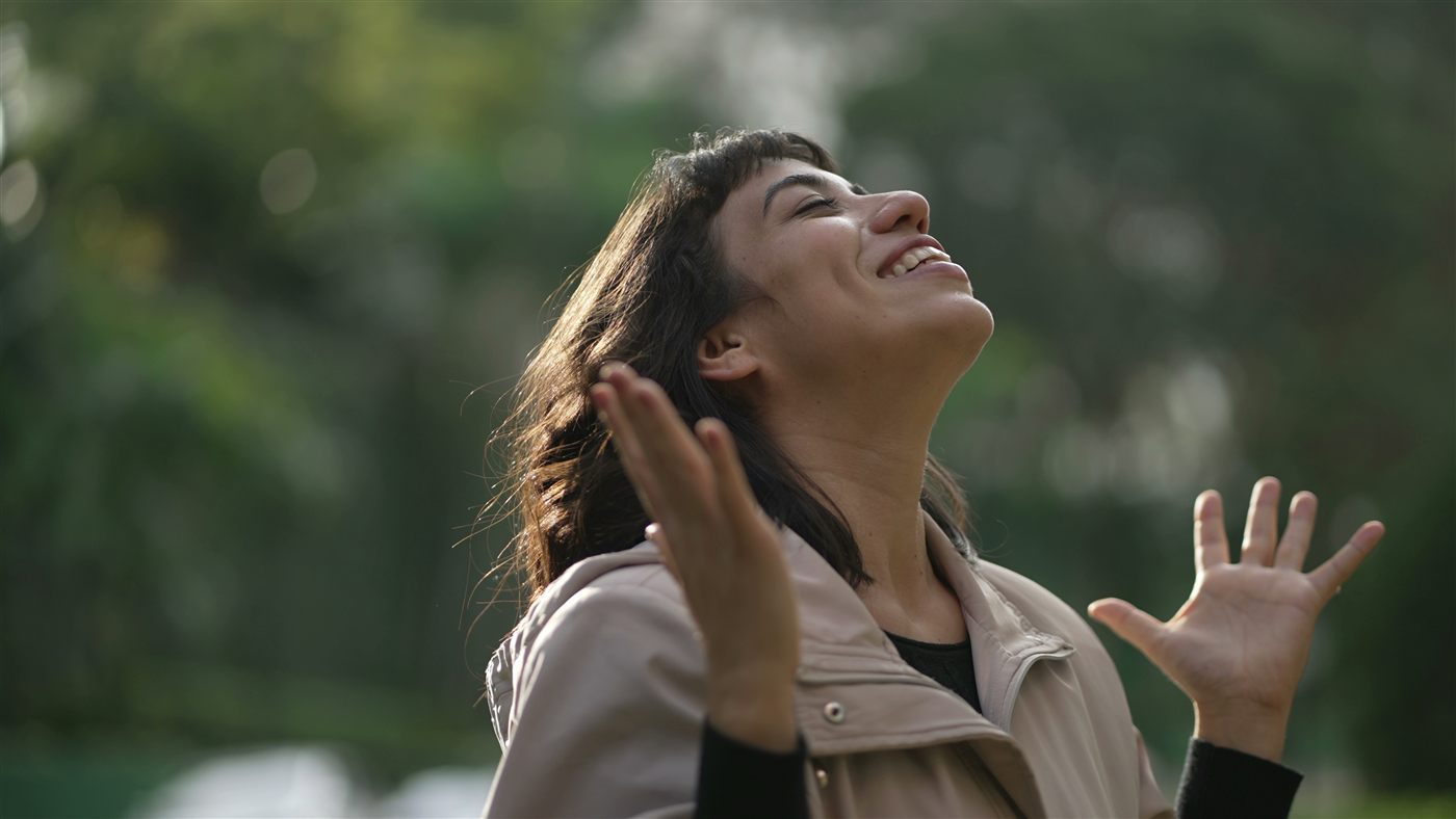 A woman in joyful prayer outdoors